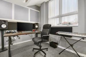 Music production studio with Yamaha studio monitors, microphones, and midi keyboard.