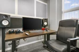 Music production studio with Yamaha studio monitors, microphones, and midi keyboard.
