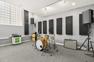 Fully backlined music practice and band rehearsal studio with drumset, amps, PA system, and sound treatment
