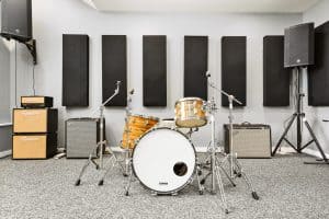 Fully backlined music practice and band rehearsal studio with drumset, amps, PA system, and sound treatment
